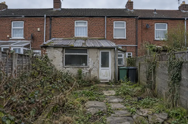 Arrière de maison avec annexe délabrée et jardin à l'abandon