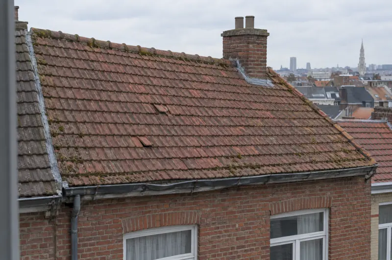 Toiture en vieilles tuiles rouges avec mousse et gouttière affaissée avant travaux